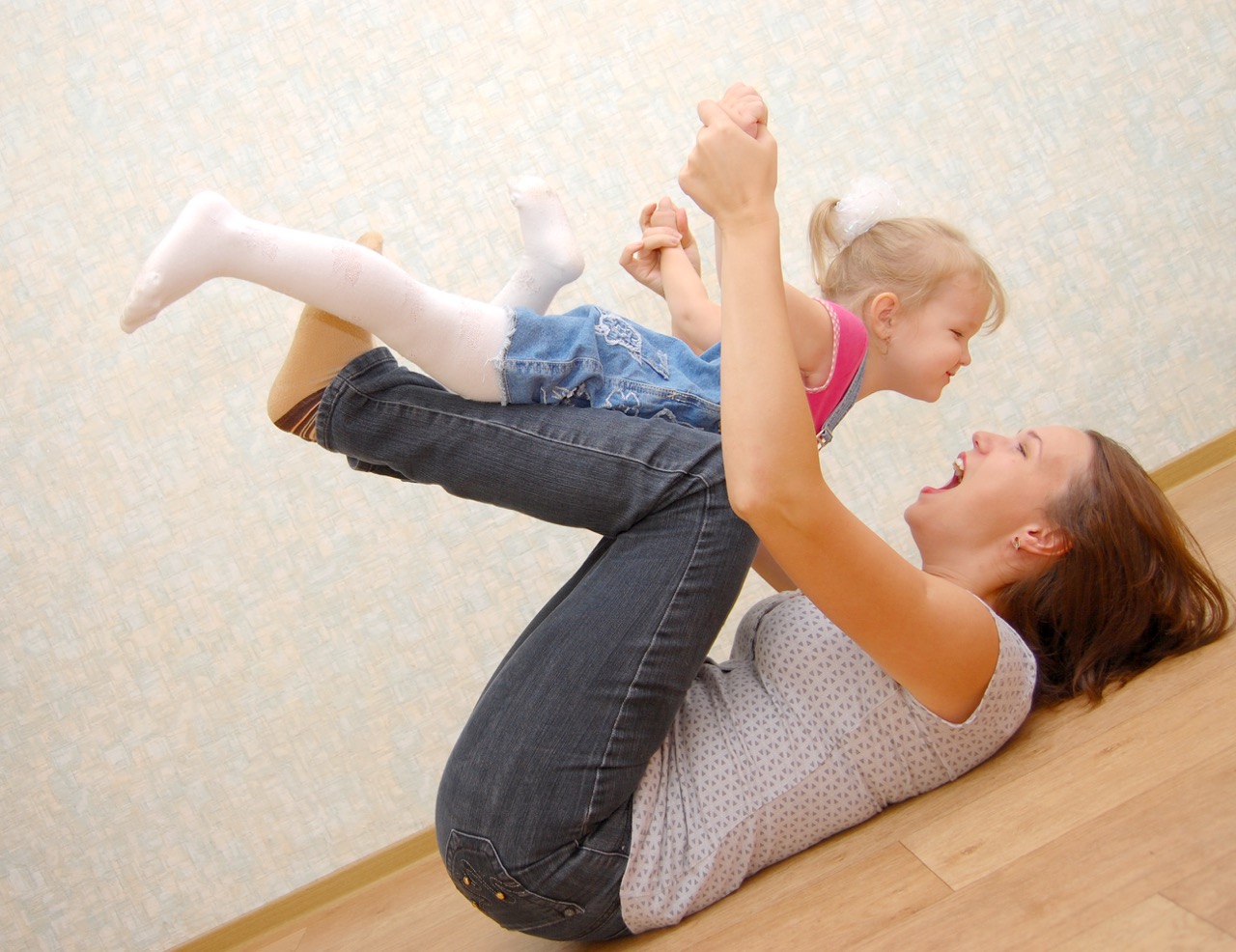 A parent lifting a laughing baby overhead